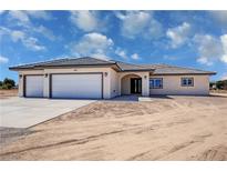 Charming single-story home featuring a three-car garage, arched entryway, and desert landscaping at 1131 Lupin St, Pahrump, NV 89048