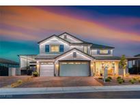 Beautiful two-story home featuring a well-manicured lawn, three-car garage, and covered front porch, illuminated by outdoor lighting at 1523 Great Sands St, Boulder City, NV 89005