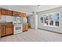 Bright kitchen features wood cabinets, tile flooring, gas range and large bay window for lots of light at 3684 Hawaii Ave, Las Vegas, NV 89104