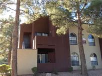 Inviting two-story condo building with a combination of light and dark stucco and mature trees at 4050 Pacific Harbors Dr # 214, Las Vegas, NV 89121