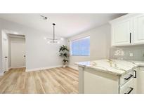 Bright kitchen features a modern light fixture, white cabinets, and light wood flooring at 744 Hubbard St, Las Vegas, NV 89110