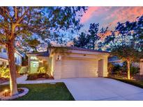 Charming single-story home with a well-manicured lawn, attached garage, and vibrant landscaping at dusk at 7837 Sea Rock Rd, Las Vegas, NV 89128