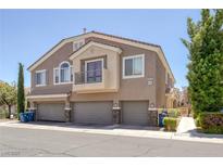 Inviting townhome featuring attached garages, tan stucco, and a charming balcony with a metal railing at 8639 Horizon Wind Ave # 102, Las Vegas, NV 89178