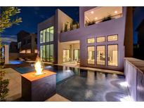 Inviting backyard pool with a fire pit, water feature, and modern home exterior at twilight at 10752 Patina Hills Ct, Las Vegas, NV 89135