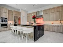 Modern kitchen with a large black marble island, stainless steel appliances, and stylish seating at 10752 Patina Hills Ct, Las Vegas, NV 89135