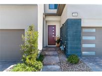 Inviting front entrance with a modern door, gray and blue facade, and well-manicured landscaping at 2530 Catallo St, Henderson, NV 89044