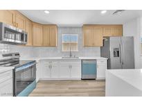 Modern kitchen featuring stainless steel appliances, white cabinets, and light wood flooring at 747 Greenbriar Townhouse Way, Las Vegas, NV 89121