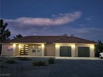 Lovely single-story home with a red tile roof, two-car garage, and desert landscaping at dusk at 871 Buol Rd, Pahrump, NV 89048