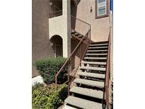Building exterior featuring stairs with brown metal handrails and some landscaping in the front at 9580 W Reno Ave # 127, Las Vegas, NV 89148