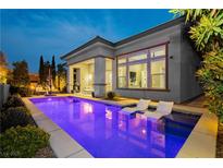 Inviting backyard pool with submerged lounge chairs and manicured landscaping at dusk at 12382 Tudor Arch Dr, Las Vegas, NV 89138