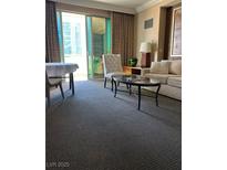 Cozy living room features carpet floors, comfortable seating, and access to a balcony with city views at 135 E Harmon Ave # 307, Las Vegas, NV 89109