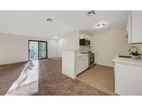 A cozy living room and adjacent modern kitchen with ample natural light and carpeted floors at 5161 Lindell Rd # 206, Las Vegas, NV 89118