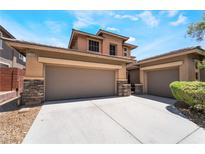 Spacious three-car garage with stone accents and a concrete driveway on a sunny day at 5568 Table Top Ln, Las Vegas, NV 89135