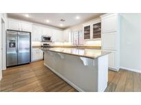 Well-lit kitchen features stainless steel appliances, white cabinets and a large island with light toned counter top at 5568 Table Top Ln, Las Vegas, NV 89135