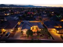 Stunning aerial view of a beautiful home, showcasing a well-manicured yard and neighborhood lights at dusk at 8149 Villa De La Playa St, Las Vegas, NV 89131
