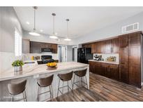 Modern kitchen with dark wood cabinets, white countertops, a kitchen island with barstools and stainless steel appliances at 209 Camino Vista St, Henderson, NV 89012