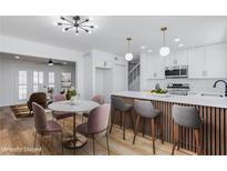 Bright kitchen and dining area boasts white cabinets, an island, and hardwood floors at 572 Tam O Shanter, Las Vegas, NV 89109