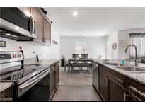 Well-lit kitchen featuring stainless steel appliances and granite countertops next to dining area at 6953 Midnight Bronze St, North Las Vegas, NV 89086
