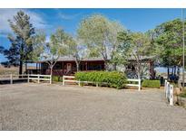 Charming single-story home with a covered porch, mature trees, and white picket fence creating a cozy curb appeal at 12992 State Hwy 160, Las Vegas, NV 89161