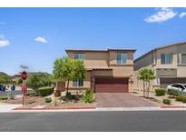 Two-story tan home featuring a brick driveway and a two-car garage at 4498 Lantern Point Ave, North Las Vegas, NV 89084