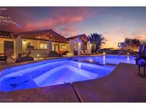 Stunning backyard pool with illuminated water, covered patios, lush landscaping at sunset at 9385 Mohawk St, Las Vegas, NV 89139