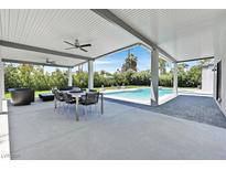 Covered patio with ceiling fans, outdoor dining, and views of the sparkling pool and lush backyard at 324 Park Way East, Las Vegas, NV 89106