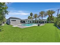 Stunning backyard featuring a sparkling pool, lush lawn, spa, and relaxing lounge area surrounded by swaying palm trees at 324 Park Way, Las Vegas, NV 89106