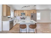 A modern kitchen with stainless steel appliances, an island with bar seating, and light wood cabinetry at 6456 First View Ave, Las Vegas, NV 89142