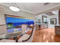 Elegant dining room with glass table, wood floors, and sliding glass doors to patio with city view at 10621 Tinta Ln, Las Vegas, NV 89144