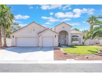 Charming home featuring a three-car garage, arched entryway, manicured lawn, and mature palm trees at 4116 Villa Flora St, Las Vegas, NV 89130