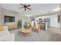 Cozy living room with modern decor, featuring an open floor plan flowing into a bright kitchen and dining area at 6460 Raven Hall St, North Las Vegas, NV 89084