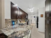 Well lit kitchen with stainless steel sink, granite countertop, and dark wood cabinets at 7952 Lonette Ave, Las Vegas, NV 89147