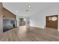 Bright living room featuring a modern fireplace, wood-look floors, and sliding glass doors to bring the outside in at 9412 Mount Cherie Ave # 102, Las Vegas, NV 89129
