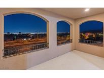 A balcony view displays an elegant design featuring arched windows that frame an illuminated cityscape at nighttime at 342 Molinetto St, Las Vegas, NV 89138