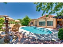 Inviting backyard pool with fountain, lush landscaping, and ample seating areas for outdoor relaxation at 3877 Platis Cir, Las Vegas, NV 89103