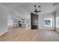 Open-concept living room featuring light wood floors, a modern fireplace, and bright white walls at 6126 Bedrock Ct, North Las Vegas, NV 89031