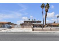 Two-story home featuring a driveway, two palm trees, a front yard, and secure fencing at 6628 Celeste Ave, Las Vegas, NV 89107