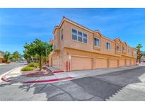 Townhome complex featuring desert landscaping, garage doors, and a red tile roof at 105 Lighthouse Dr # 105, Boulder City, NV 89005
