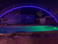 Backyard pool with blue lights, truck parked nearby under metal arch at 1818 Waldman Ave, Las Vegas, NV 89102