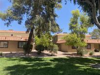 Charming condo featuring a red tile roof, complemented by mature trees and a lush green lawn at 1843 Mimosa Ct, Henderson, NV 89014