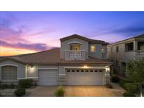 Charming home featuring a two-car garage, a Juliet balcony and a manicured front yard at twilight at 694 Value Ridge Ave, Henderson, NV 89012
