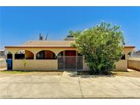 Charming single-story home featuring a gated entrance, lush landscaping and a tan exterior at 744 Mcknight St, Las Vegas, NV 89101