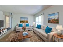 Bright living room featuring neutral walls, sofas with blue accent pillows, and natural light at 4990 River Glen Dr # 171, Las Vegas, NV 89103