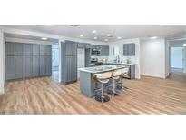 Bright kitchen features gray cabinets, island with seating, stainless appliances, and hardwood-style flooring at 6517 Villa Mesa Dr, Las Vegas, NV 89107