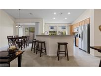 Open-concept kitchen features bar seating, stainless steel appliances, and lots of natural light at 9256 Blue Flax Pl, Las Vegas, NV 89148