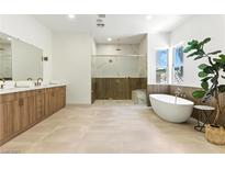 This modern bathroom features a soaking tub, glass enclosed shower, and a wood vanity at 9408 Players Canyon Ct, Las Vegas, NV 89144