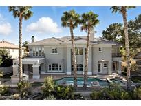 Luxurious two-story home featuring a private pool, lush landscaping, and elegant architectural details at 9408 Players Canyon Ct, Las Vegas, NV 89144