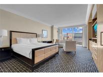 Cozy bedroom featuring a king-size bed, sitting area, and large windows with a cityscape view at 2000 Fashion Show Dr # 2400, Las Vegas, NV 89109