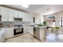 Modern kitchen featuring white cabinets, stainless steel appliances, and a stylish backsplash at 2723 Seabridge Dr, Las Vegas, NV 89121