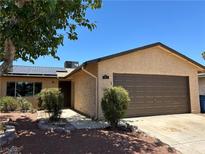 Charming single-story home featuring a brown garage door and solar panels on the roof at 608 Watkins Dr, Las Vegas, NV 89107